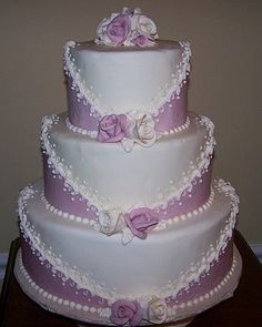 a three tiered wedding cake with purple and white decorations