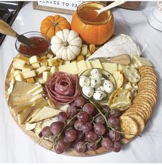 a platter filled with cheese, crackers, grapes and other foods on a table