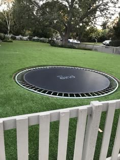 a trampoline in the middle of a yard with white picket fence around it