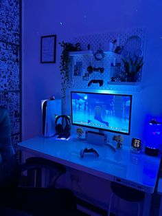 a desk with a computer and headphones lit up by blue lights in the dark