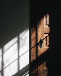 an open door with the light coming through it's glass panes and casting a shadow on the wall