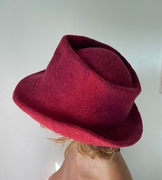 This one of a kind felted hat was made of Merino and Bergschaf wool. The main colours are red, burgundy and black. The hat was made in one piece on a resist. The resist was covered with wool fibres, which were manually rolled for many hours using only warm soapy water. The felted cone was further  manipulated into a fedora hat shape. The hat is water repellent and great for travelling as it will retain its shape even when folded flat in a bag or a suitcase. For care instructions please refer to Wool Cloche Hat, Wool Fedora Hat, Fabric Flower Brooch, Wool Fedora, Felting Tutorials, Hand Felted, Fedora Hat, Flower Brooch, Main Colors