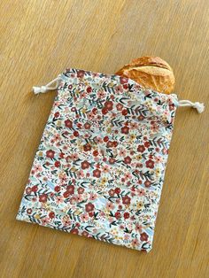 a piece of bread sitting on top of a wooden table next to a flowered bag