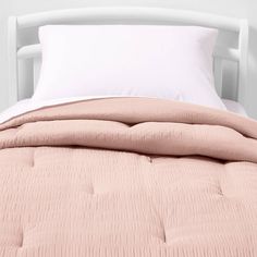 a bed with white pillows and pink comforter