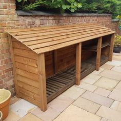 a wooden dog house built into the side of a brick wall next to a potted plant