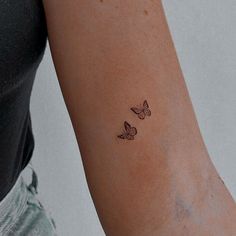 a woman's arm with two small butterflies on the left side of her arm