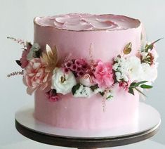 a pink cake decorated with flowers and leaves