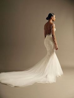 a woman in a white wedding dress is posing for the camera with her back to the camera