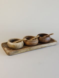 three wooden bowls and spoons on a tray