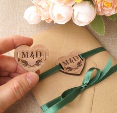 two wooden heart shaped magnets with the word m & d on them, tied to a brown envelope