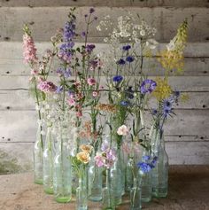 a group of vases filled with flowers on top of a wooden table