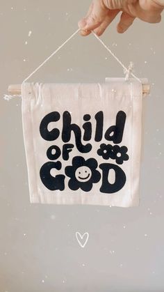 a hand holding a sign with the words child of god hanging from it's side