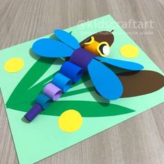 a paper cut out of a dragonfly sitting on top of a table