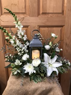 a lantern with white flowers and greenery in front of a door