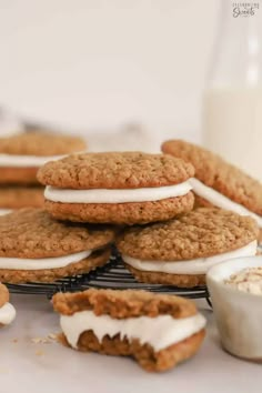 cookies and marshmallows are stacked on a cooling rack next to a glass of milk