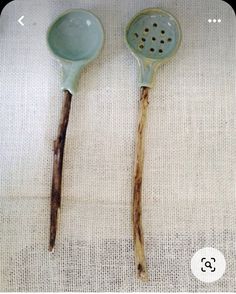 two wooden spoons sitting next to each other on top of a white table cloth