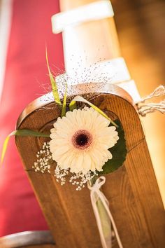 a white flower is placed on the back of a wooden chair at a wedding ceremony