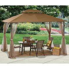 a patio gazebo with curtains and chairs on the ground in front of a lawn