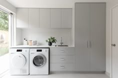 a washer and dryer in a white room with cabinets on either side of the door