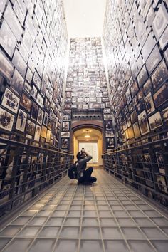 a man sitting in the middle of a room filled with framed pictures on walls and floor