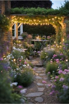 a garden with lights strung over it and flowers in the foreground, next to a stone path