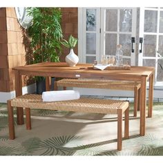 a wooden table with two benches next to a potted plant and glass door in the background