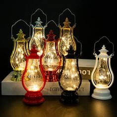 five different colored glass lanterns with fairy lights on top of each one, sitting on a white box