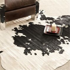 a cowhide rug with a candle on it in front of a brown leather chair