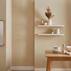 a table with plates, cups and vases on it next to a wall mounted shelf