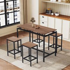 a kitchen table with four stools in front of a window and a rug on the floor