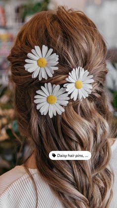 the back of a woman's head with three daisies in her hair