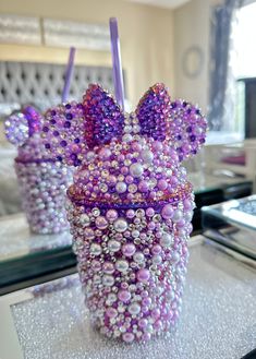 a glass with beads and bows on it sitting on a table in front of a mirror