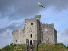 two people standing in front of a castle with a flag on it's roof