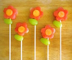 four lollipops with flowers on them sitting on top of a wooden table