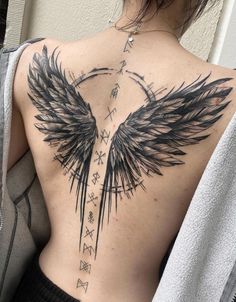 a woman's back with wings and arrows tattoo on her left side ribcage