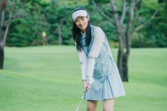 a woman in a blue dress is playing golf