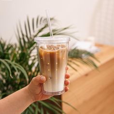 a person holding up a drink in a plastic cup with a straw and ice on top