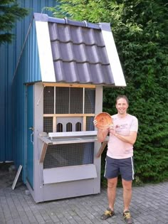 a man standing in front of a bird house holding an orange frisbee and looking at the camera