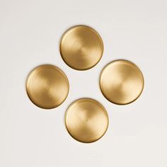 four brass plates sitting on top of a white surface