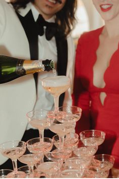 a man pouring champagne into wine glasses on top of a table with people in the background