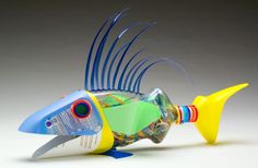 a fish shaped glass bottle with blue and yellow finks on it's head