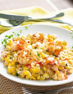 shrimp, corn and feta salad on a white plate with silver utensils