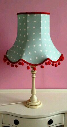 a lamp that is on top of a white table in front of a pink wall