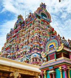 an elaborately decorated hindu temple with blue sky and clouds in the backgroud