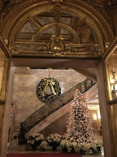 a christmas tree in the middle of a room with stairs and decorations on either side