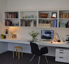 a desk with two chairs and a computer on top of it in front of a bookshelf