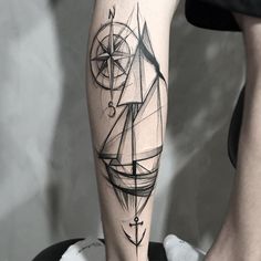 a black and white photo of a person's leg with a compass tattoo on it