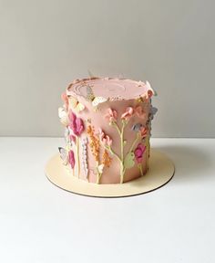 a pink cake decorated with flowers and butterflies