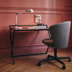 a desk with a chair, lamp and pictures on the wall