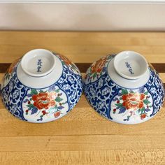 two blue and white vases sitting on top of a wooden table next to each other